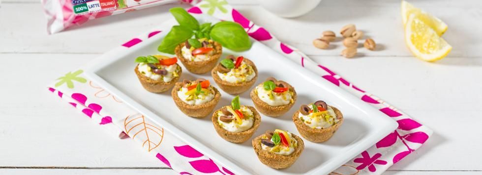 Canapè di frolla al basilico con ripieno di certosa e decorazione con olive e pistacchi