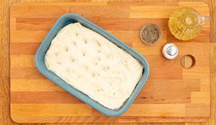 Prendete una teglia, ungetela d'olio extravergine d'oliva e con l'ausilio delle mani stendete la pasta di modo che abbia uno spessore di 1 centimetro