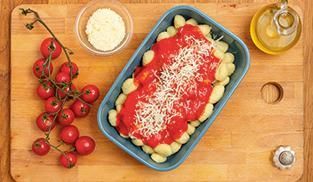 Mettete gli gnocchi in una pirofila da forno, cospargeteli con il sugo Mettete gli gnocchi in una pirofila da forno, cospargeteli con il sugo